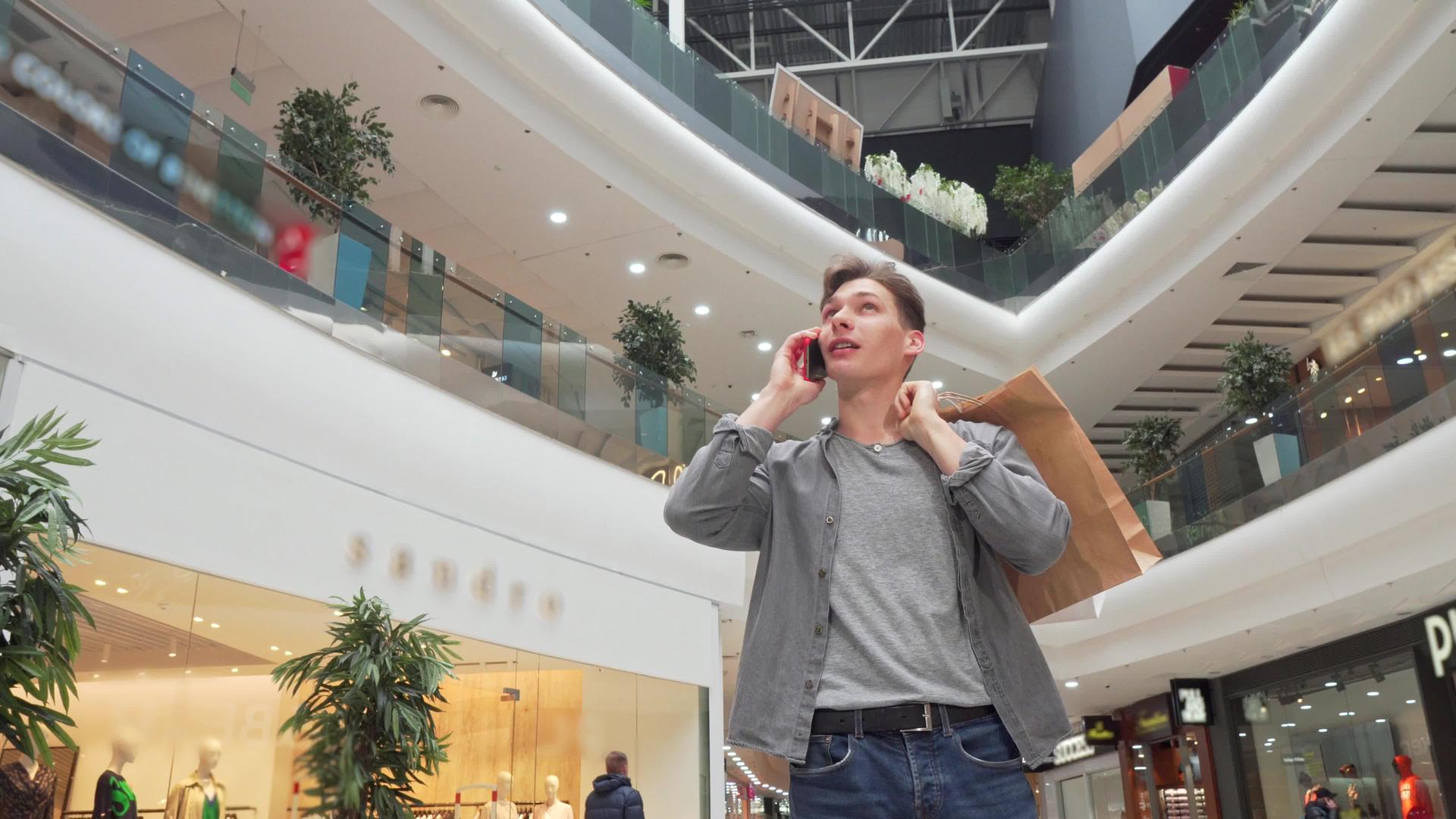 年轻人在购物中心的电话里说话视频的预览图