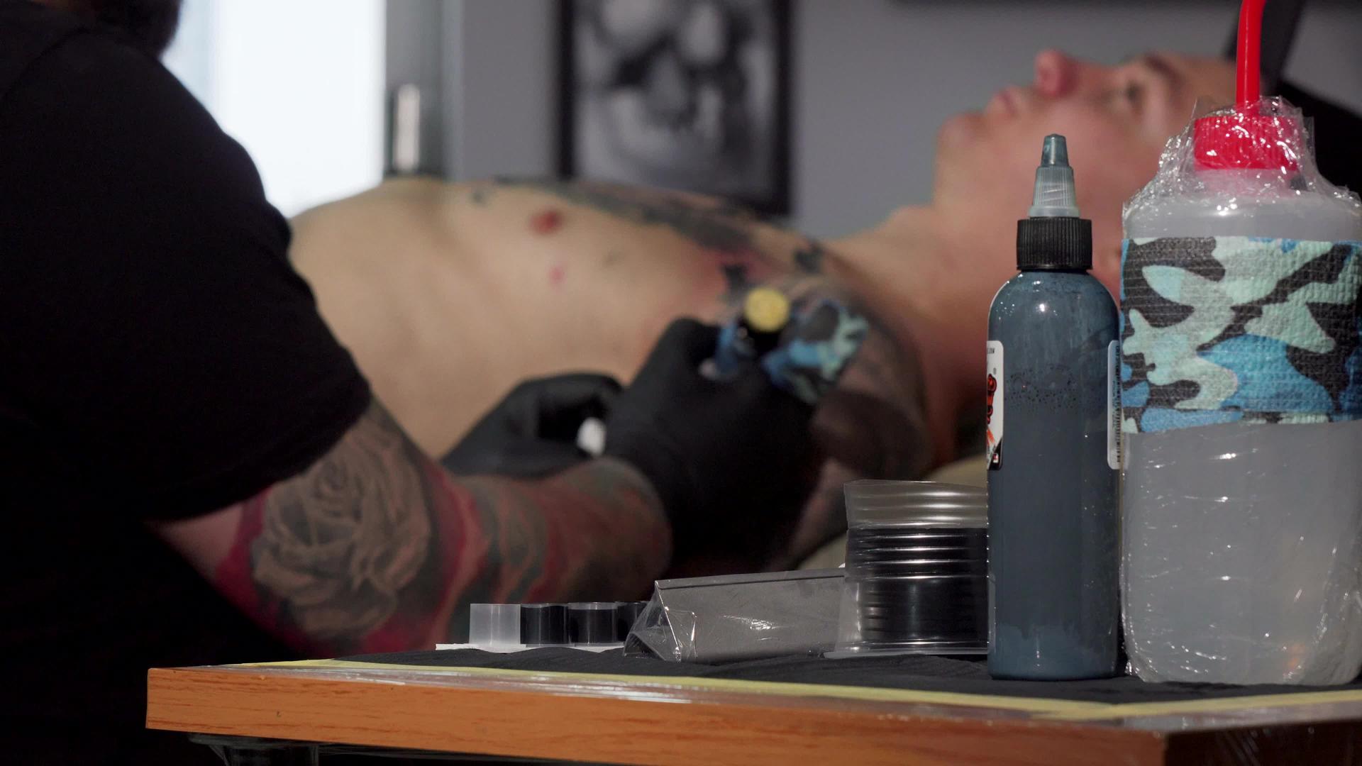 在工作室工作的纹身艺术家在客户的胸前做了一个纹身艺术家视频的预览图
