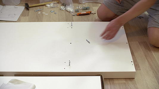 男人用螺丝刀在地板上组装新的家居家具修理工用螺丝刀视频的预览图
