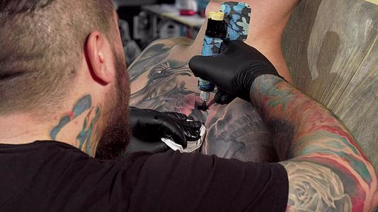 一位纹身艺术家在男性顾客的胸部做了后视镜头视频的预览图