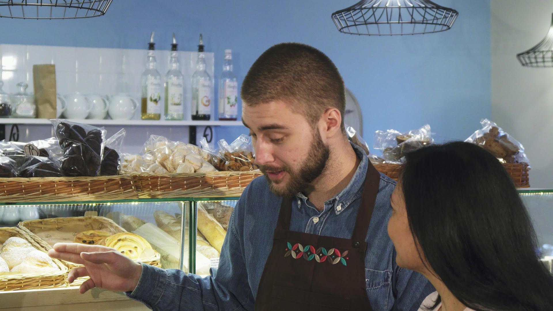 在她的店里工作的专业男性面包师帮助她们成熟的女性顾客视频的预览图