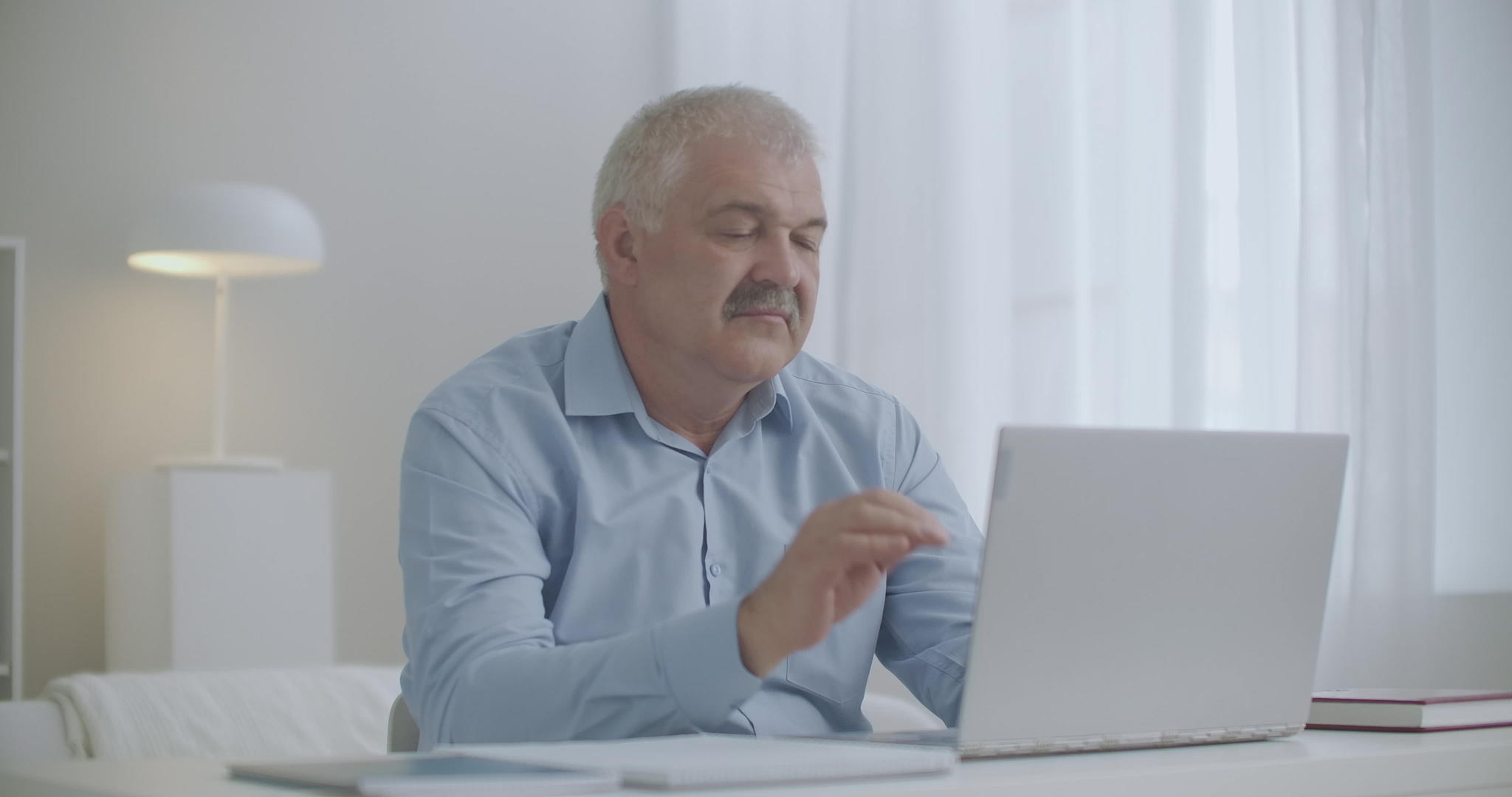 患有颈骨质疏松症中毒的中年男性正在使用笔记本电脑工作视频的预览图