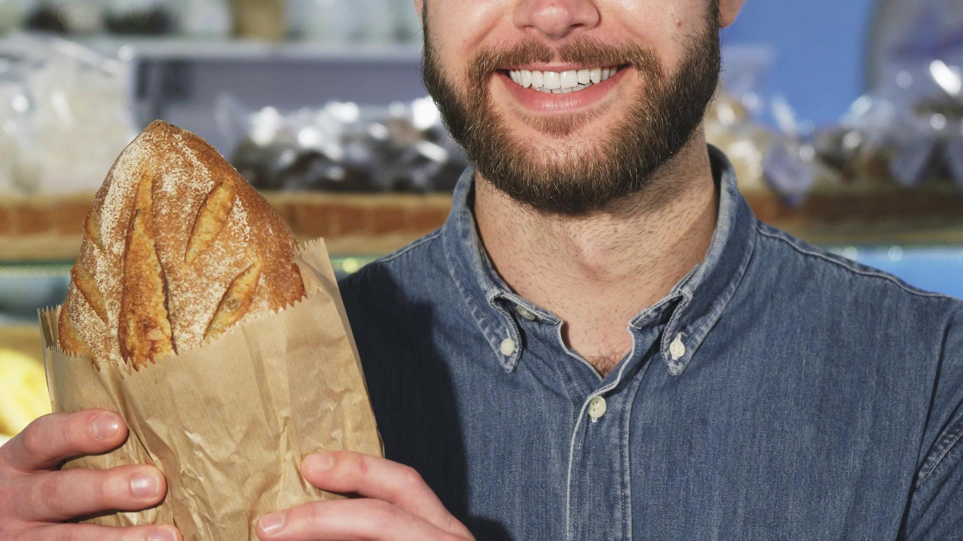 一个长胡子的男人拿着一个面包蛋糕里面有一个新鲜的面包视频的预览图