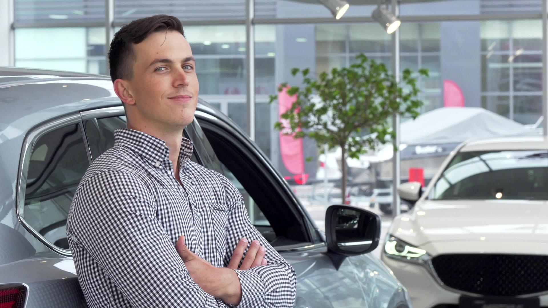 帅哥如梦般微笑靠在经销店的新车上视频的预览图