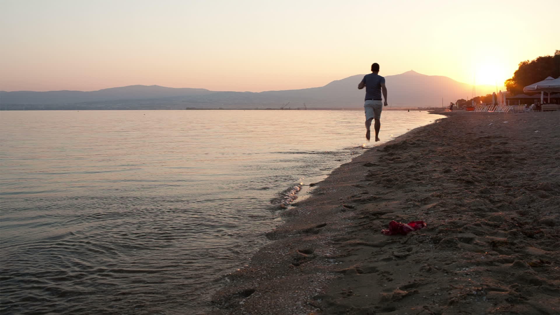 日落时男子在海滩上奔跑视频的预览图