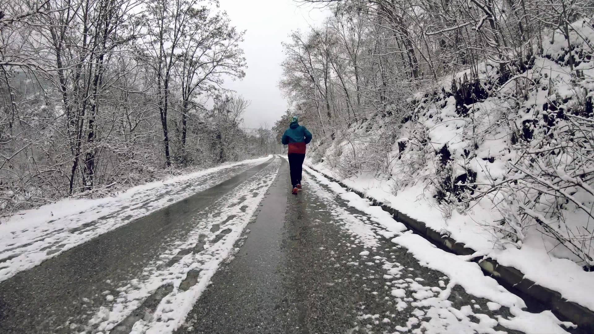 冬天男人在农村的雪路上在森林里奔跑视频的预览图