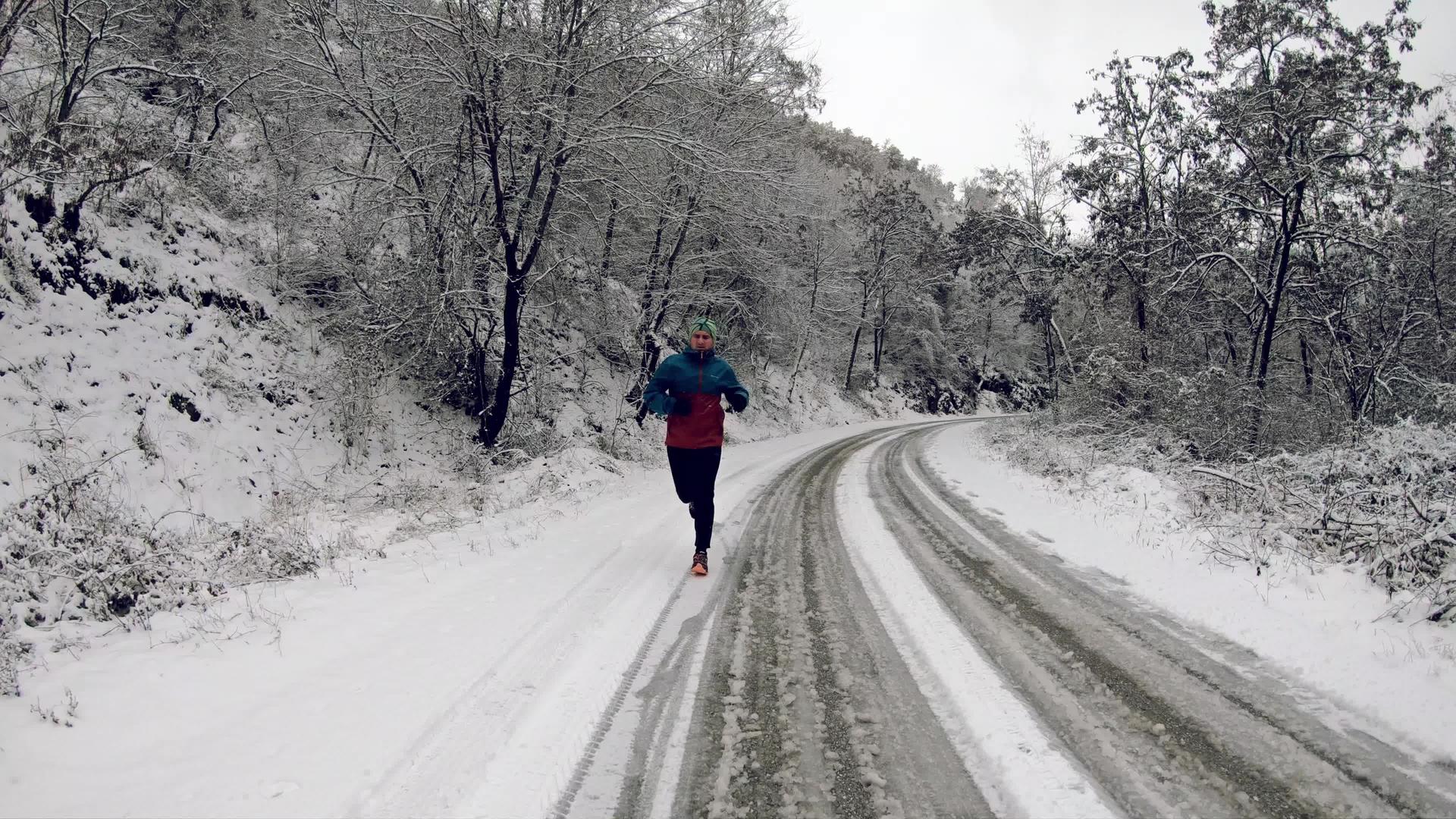 在乡间路上慢跑的人在寒冷的冬天下雪慢慢移动视频的预览图