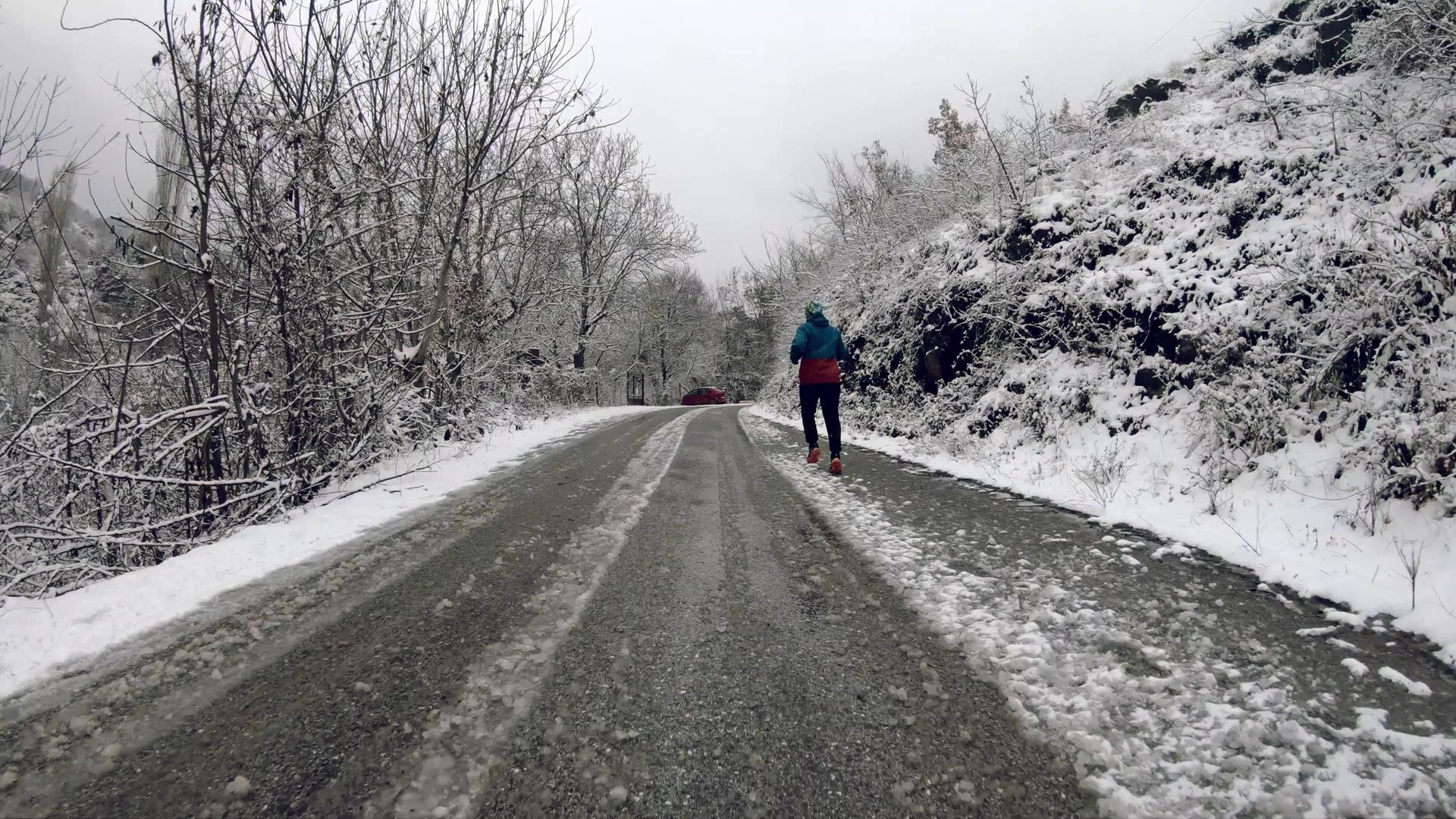 年轻人在雪上奔跑覆盖着冬天乡村道路的慢动作视频的预览图