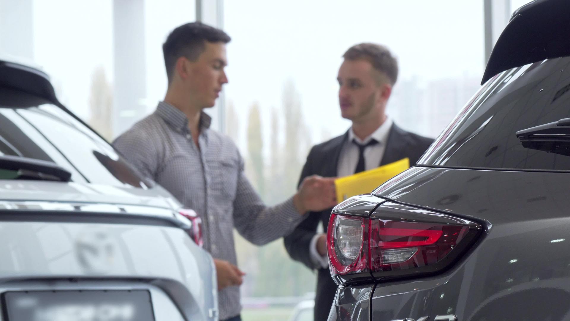 在背景中男性客户与汽车经销商交谈选择性地选择汽车视频的预览图