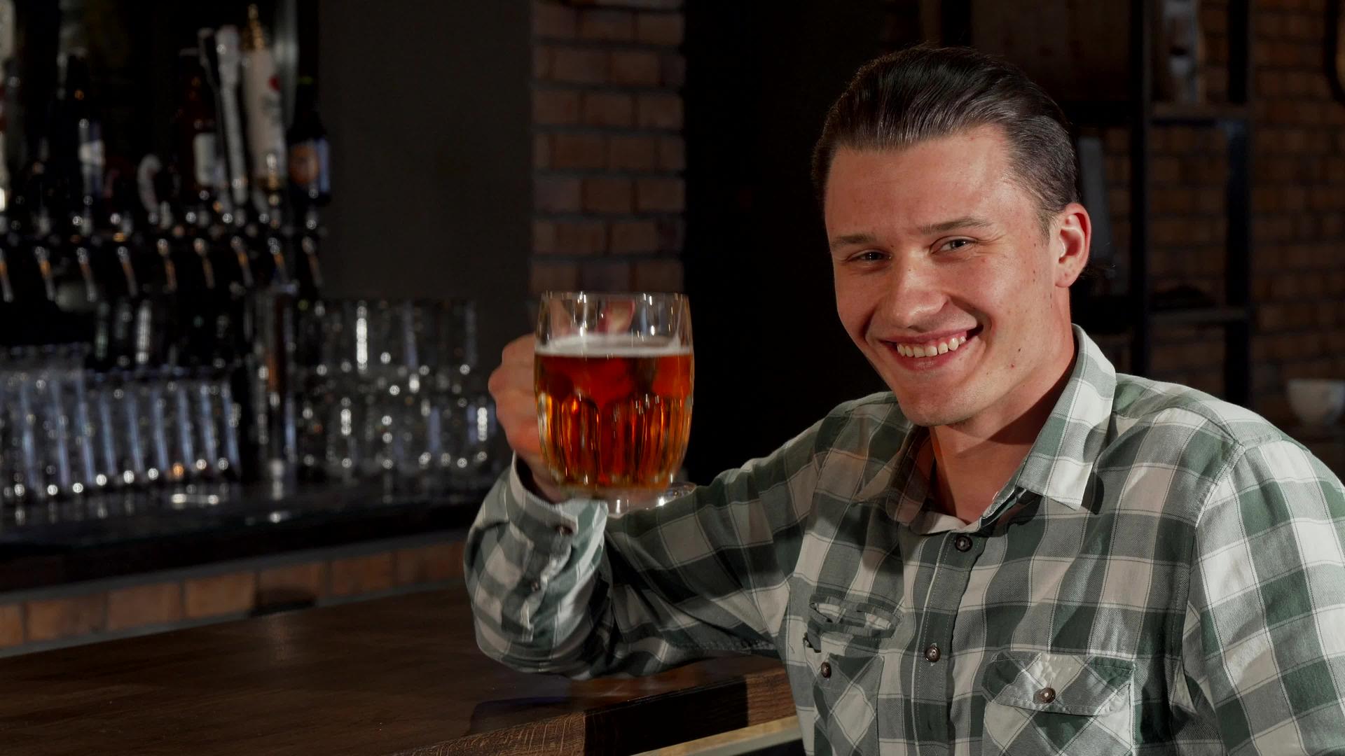 英俊快乐的男人微笑着举杯相机庆祝啤酒杯视频的预览图