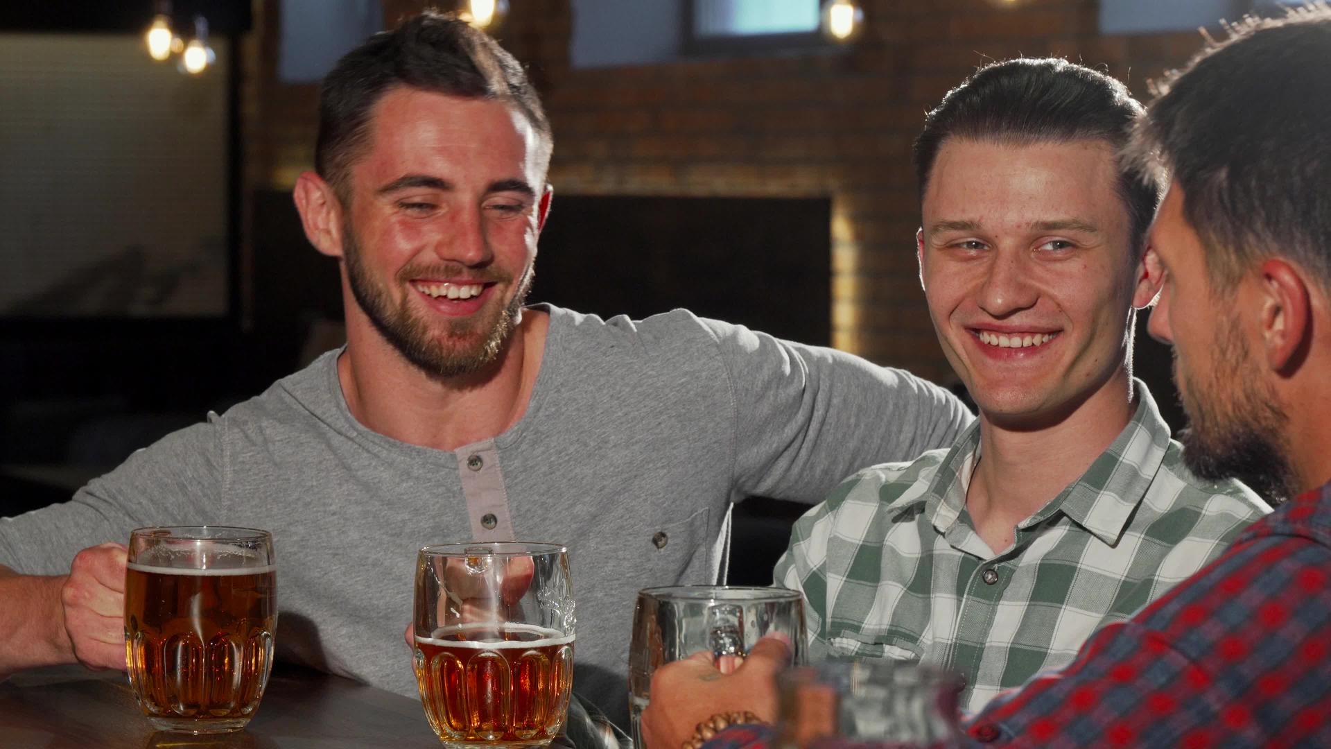 一群男性朋友在酒吧里喝啤酒杯和啤酒杯视频的预览图