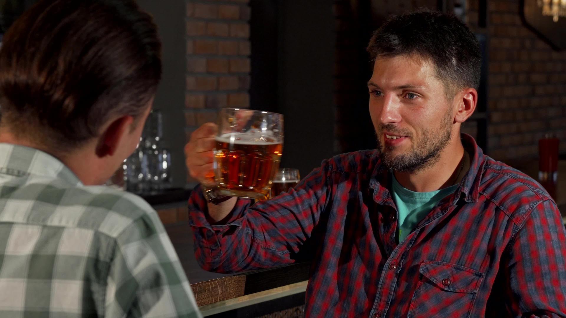 在酒吧喝啤酒时与朋友交谈的成熟胡子男子在酒吧喝酒视频的预览图