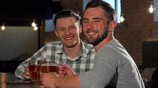 快乐的男人对着镜头微笑在酒吧喝啤酒视频的预览图