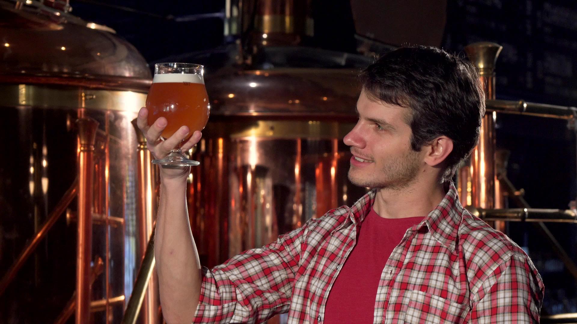 快乐的男酿酒师对着镜头微笑在杯子里检查啤酒视频的预览图