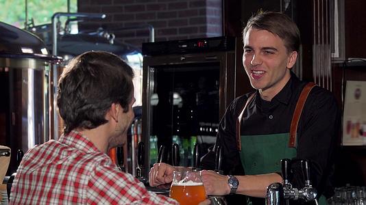 快乐的男人在当地酒吧喝啤酒时和酒保聊天视频的预览图