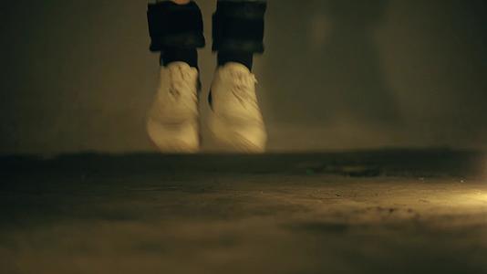 穿着白色运动鞋和黑色脚踝重量的双腿近距离合拍跳过视频的预览图