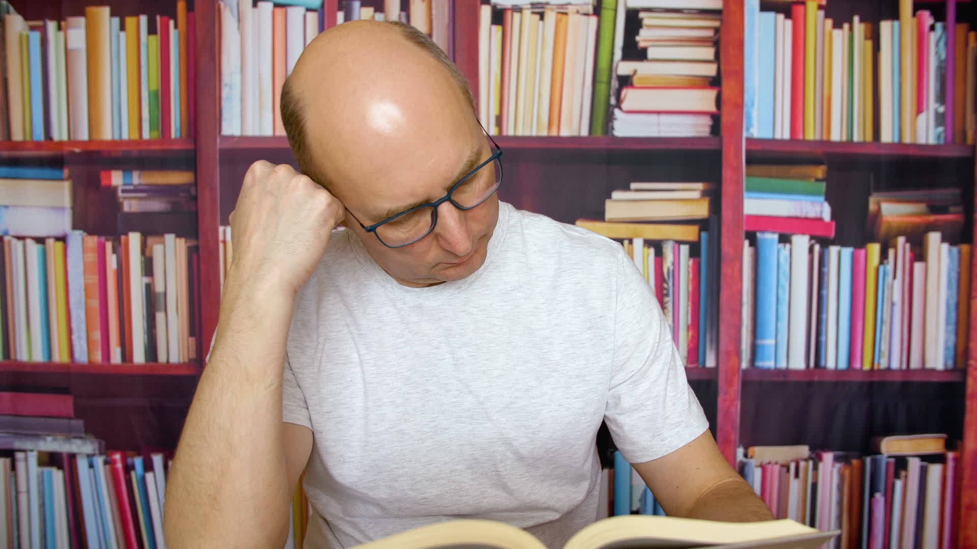 书架的背景在家庭图书馆的桌子上秃头的人头上有一本书视频的预览图