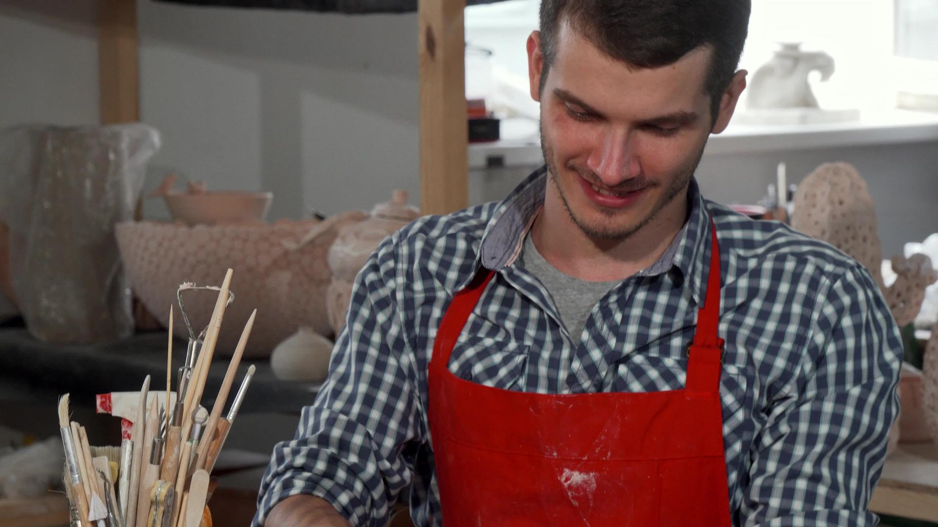 英俊、英俊、快乐的男陶匠喜欢在工作室工作视频的预览图