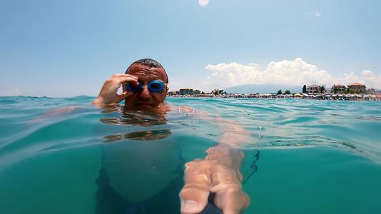 游泳运动员戴着护目镜在清澈的水晶中潜水视频的预览图