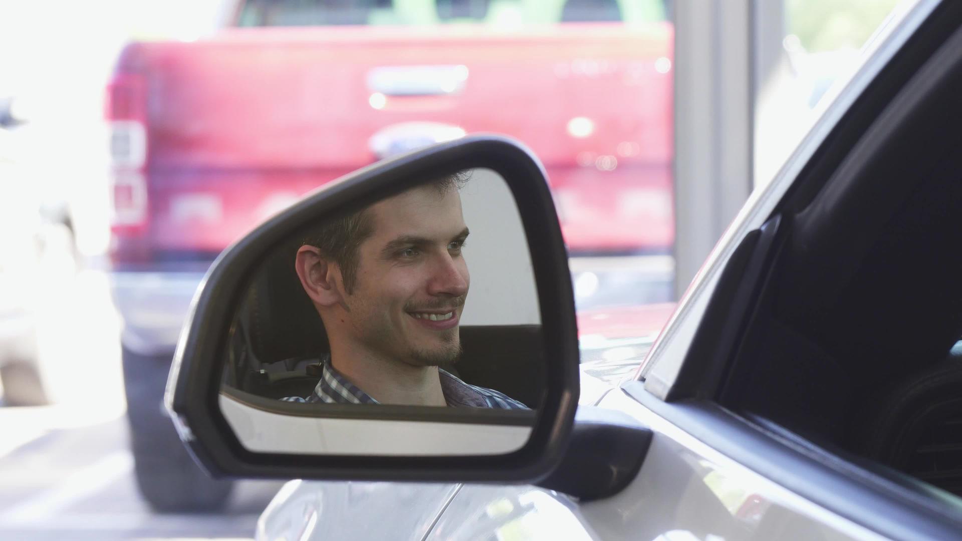 快乐的男司机微笑着靠近汽车的侧镜视频的预览图