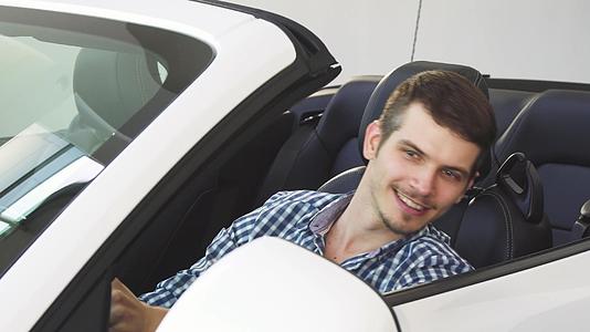 一个拿着车钥匙的年轻人坐在车里司机英俊快乐视频的预览图