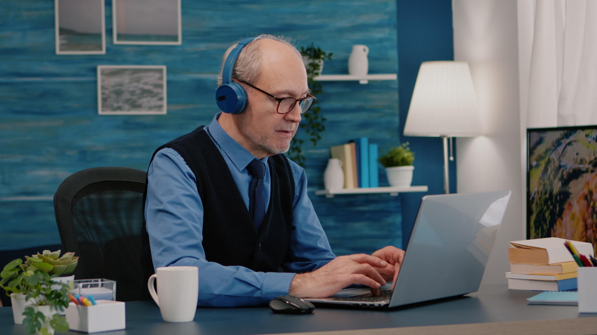 关键的老企业家耳机在笔记本电脑上听音乐打字视频的预览图