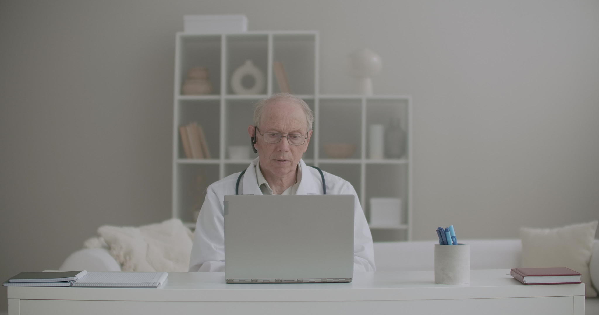老年男性医生使用笔记本电脑在门诊远程工作视频的预览图