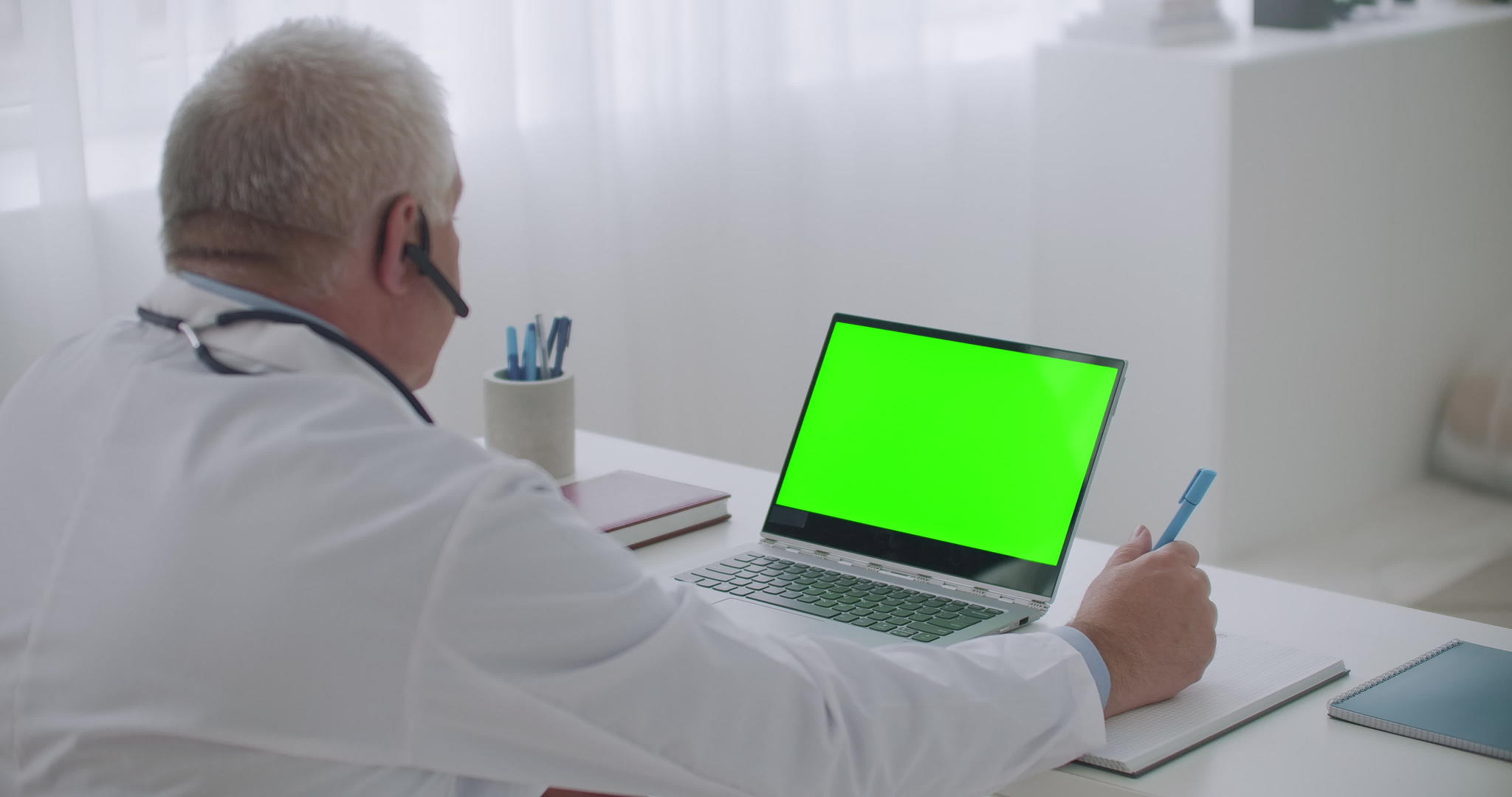 男医生在办公室的笔记本电脑上用绿色显示屏查看颜色视频的预览图