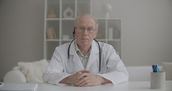老年男医生坐在诊所在线视频聊天点头视频会议上视频的预览图