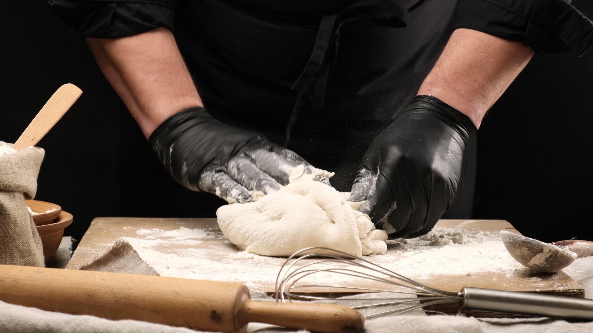 黑色乳胶手套厨师在圆木上准备白小麦面粉面团视频的预览图