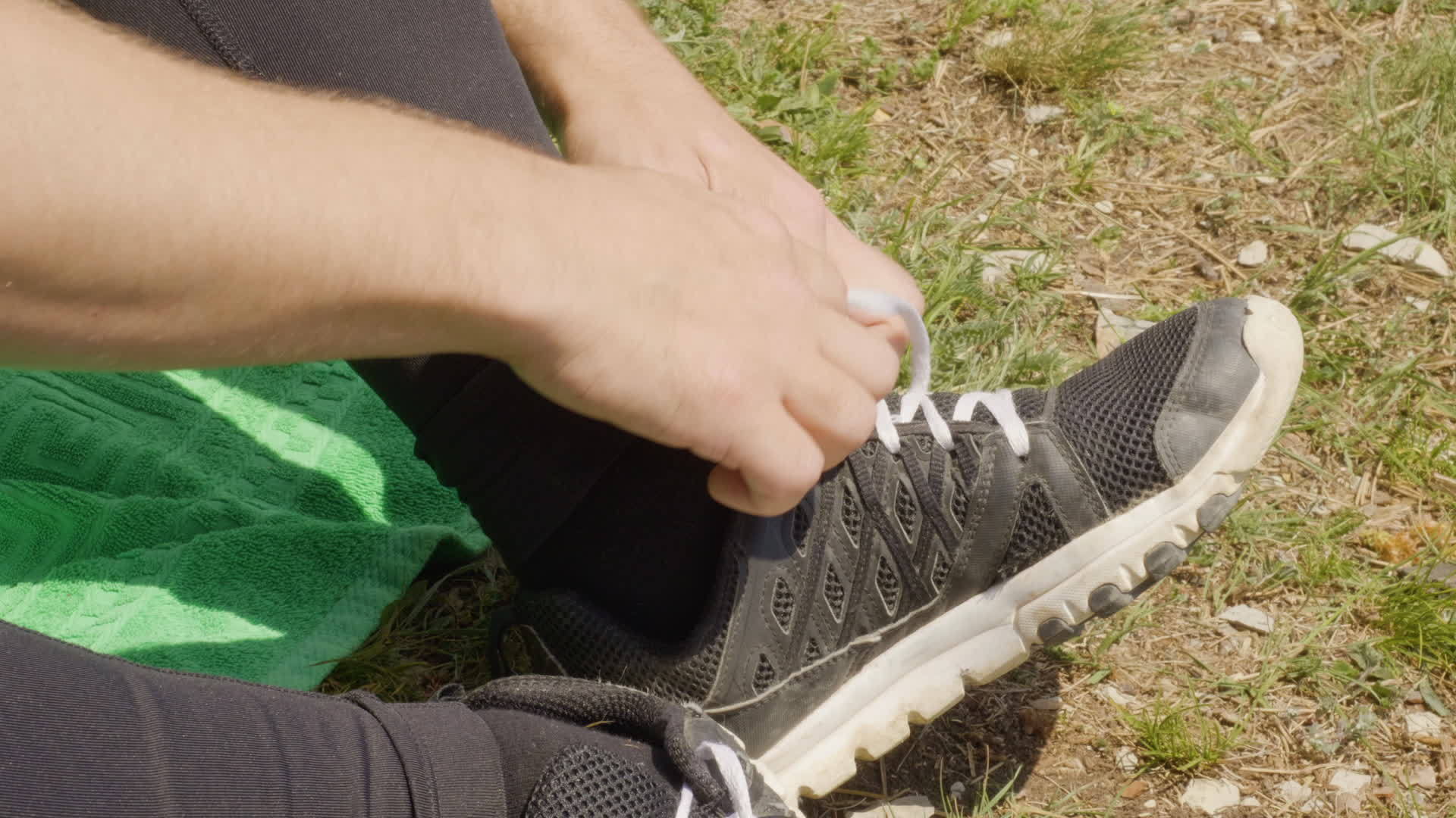 男人在户外休息时解开运动鞋上的鞋带男人坐在草地上视频的预览图