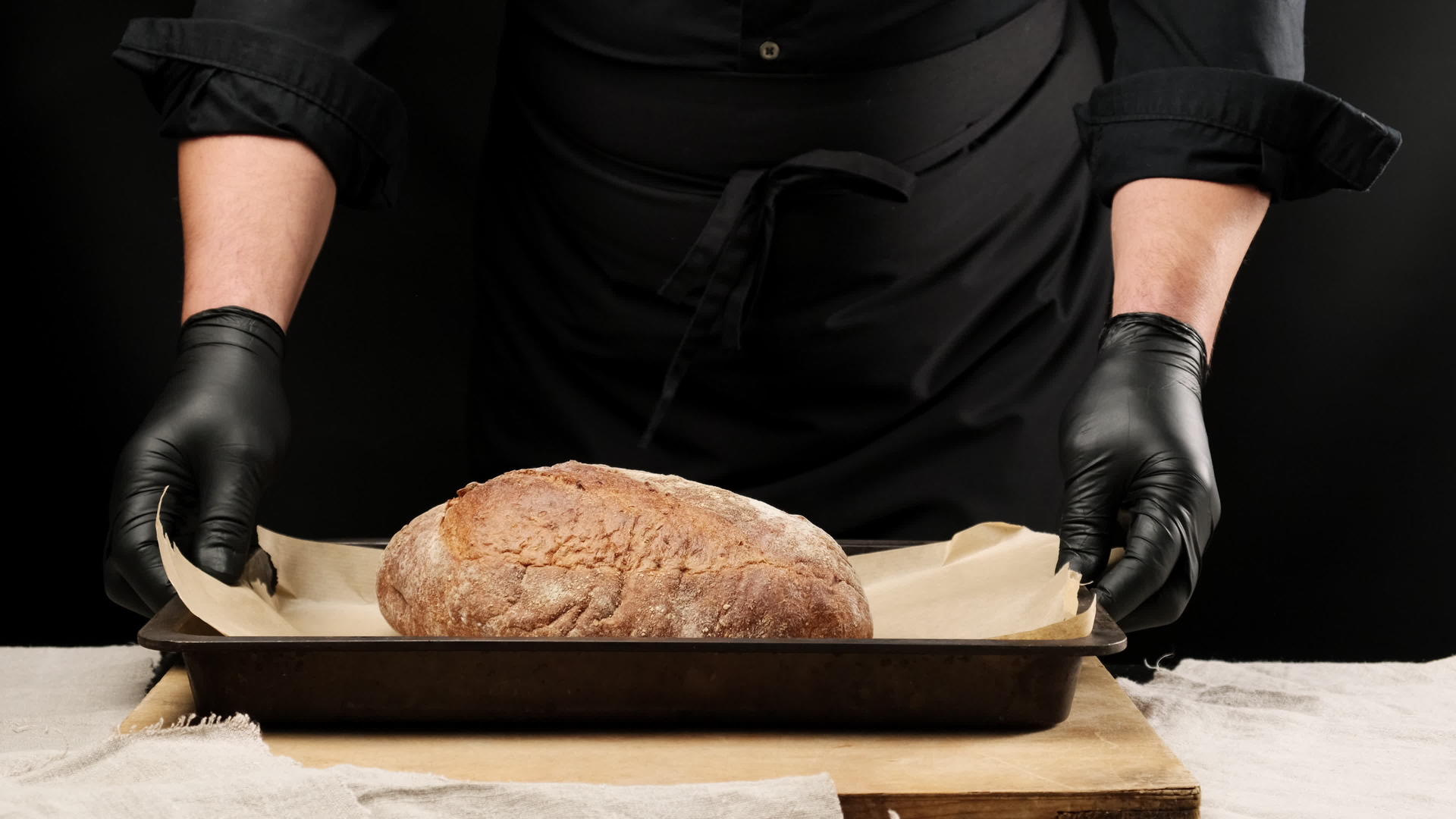 穿着黑色制服的厨师在桌子上放了一个金属烤盘背面有一个黑色圆圈视频的预览图