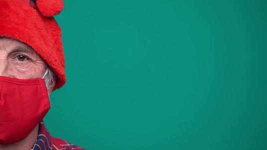 红色面具和圣诞老人帽子的成熟男子肖像看着相机视频的预览图