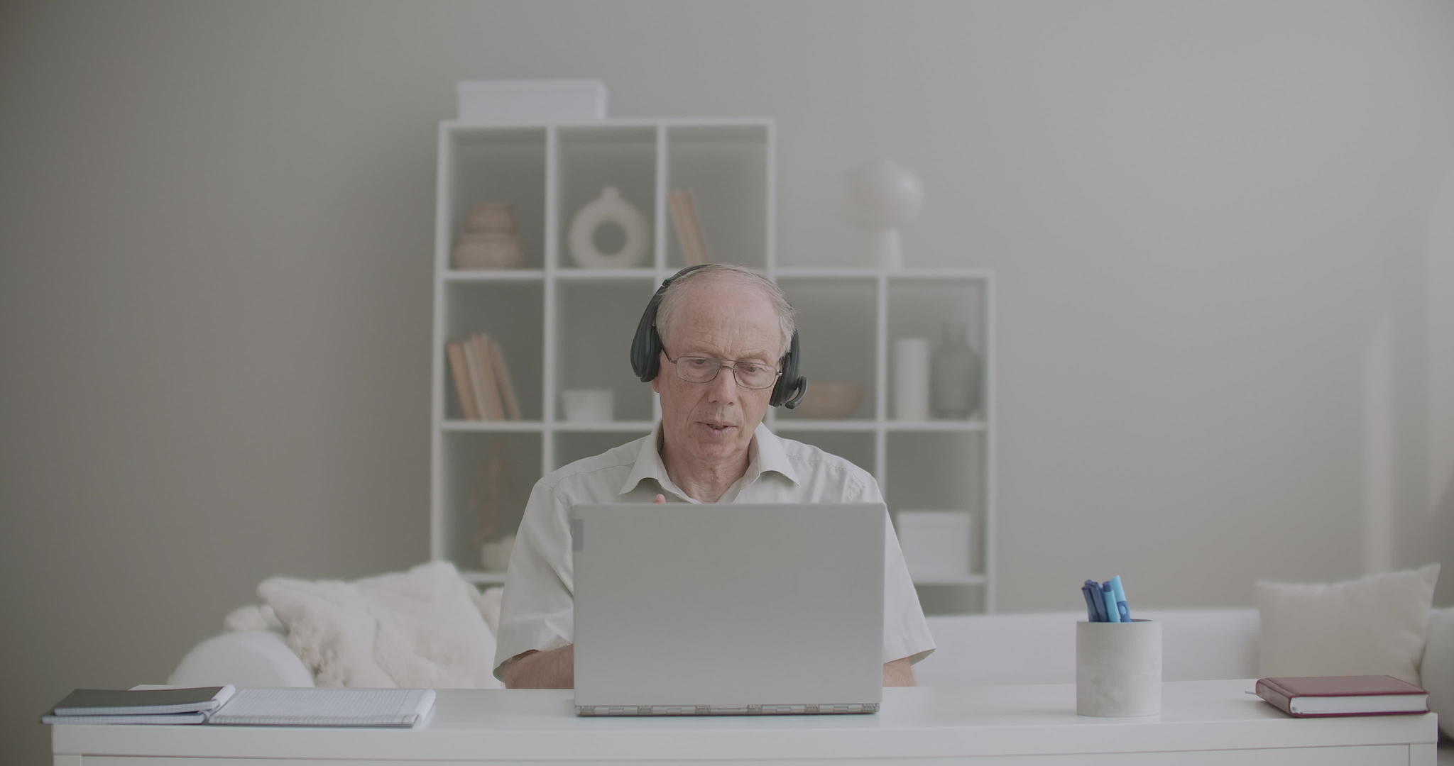 老年男教师在线教学呆在家里使用互联网连接和耳机视频的预览图