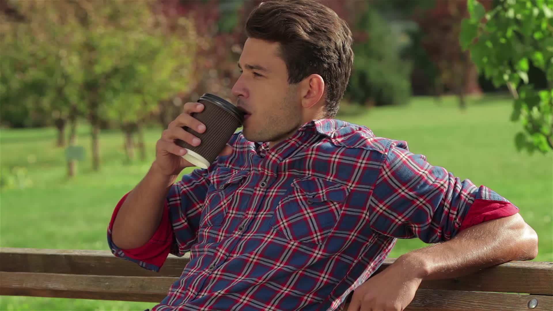 男人在公园长椅上喝咖啡和咖啡视频的预览图