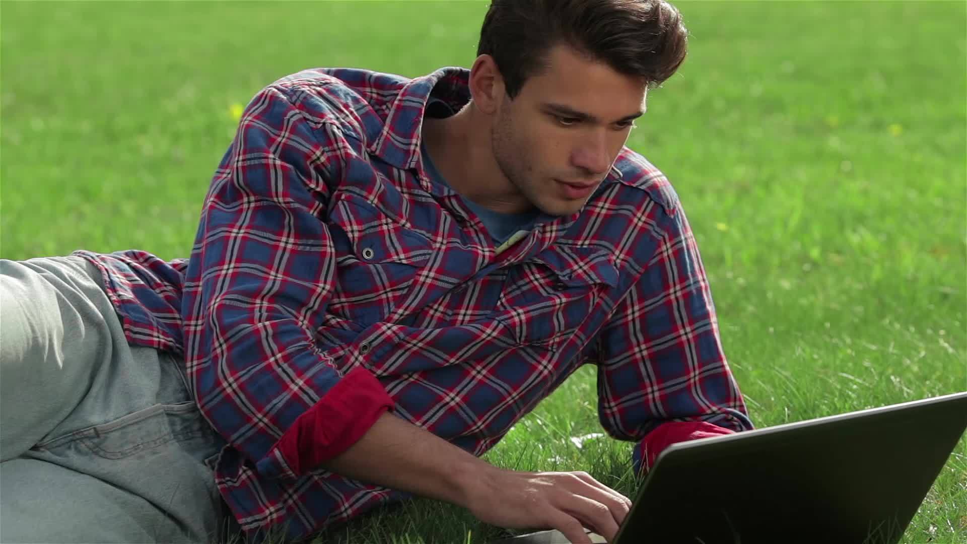 英俊的年轻人躺在草地上视频的预览图
