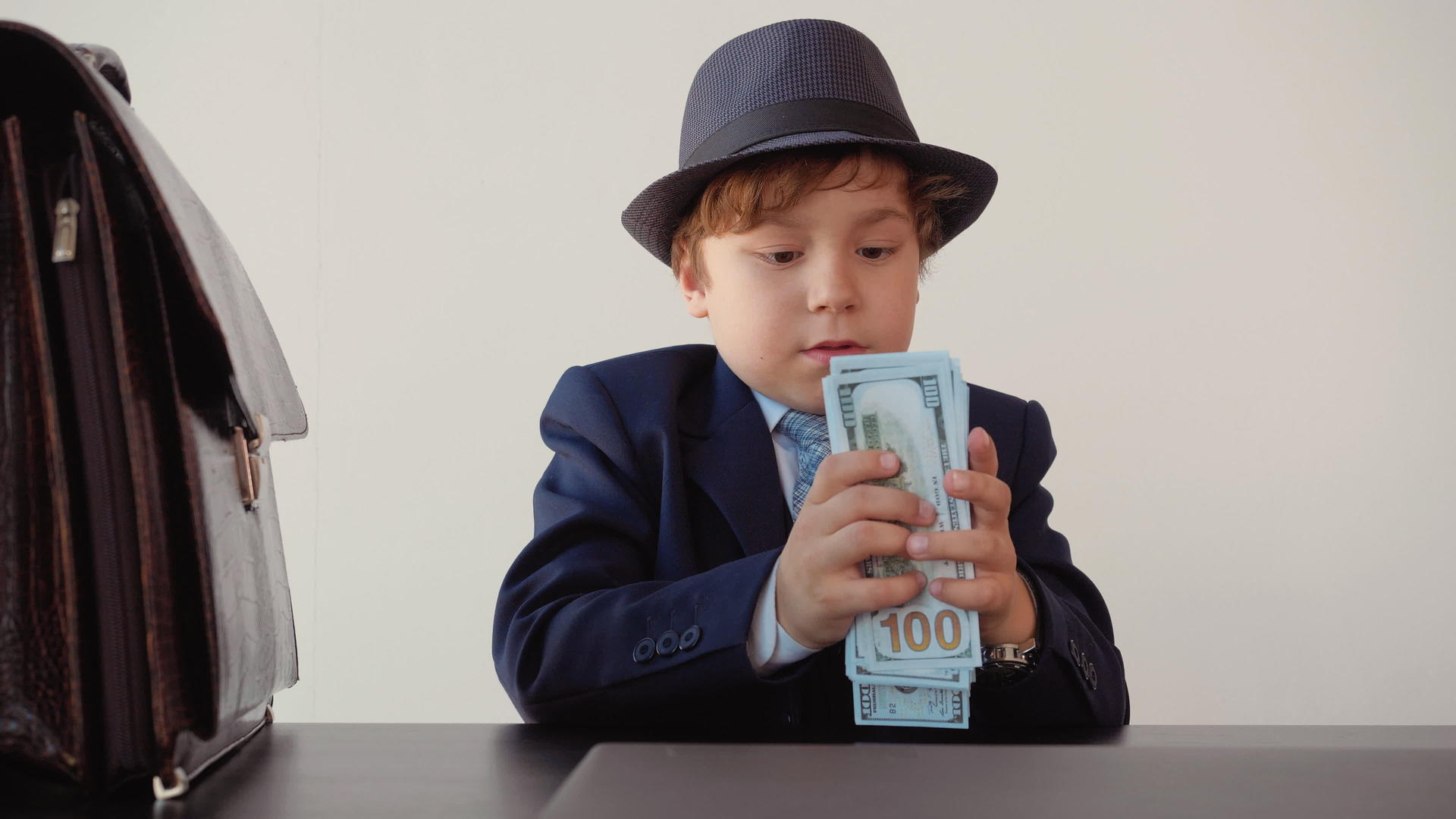 上衣男孩的小企业家在他的办公室里放了100美元的钞票视频的预览图