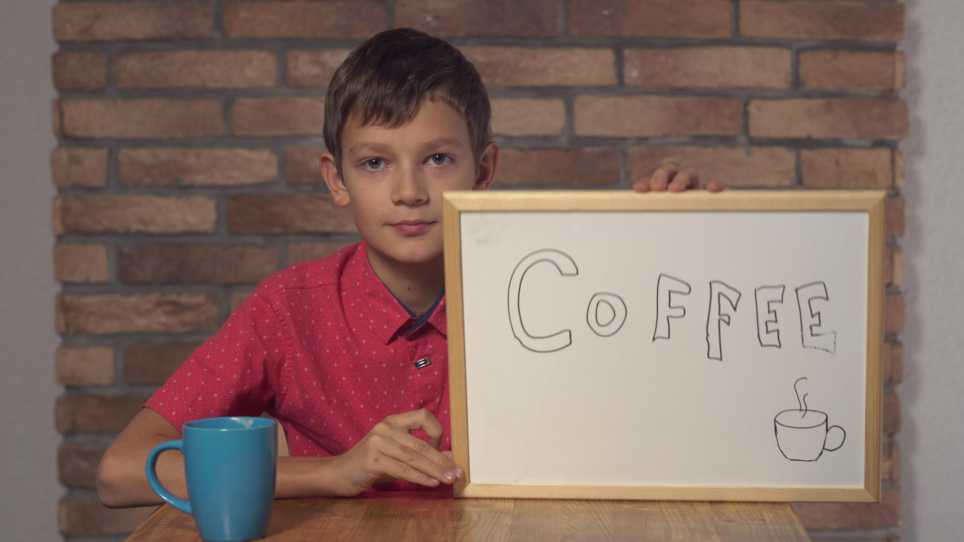 坐在桌旁的孩子拿着翻页的照片在红砖墙上放着咖啡纸视频的预览图