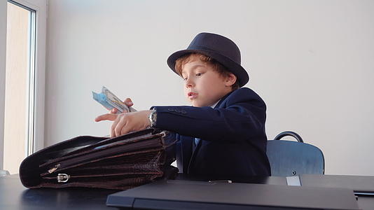 这个小男孩看起来像一个企业家把钱藏在公文包里笑着视频的预览图