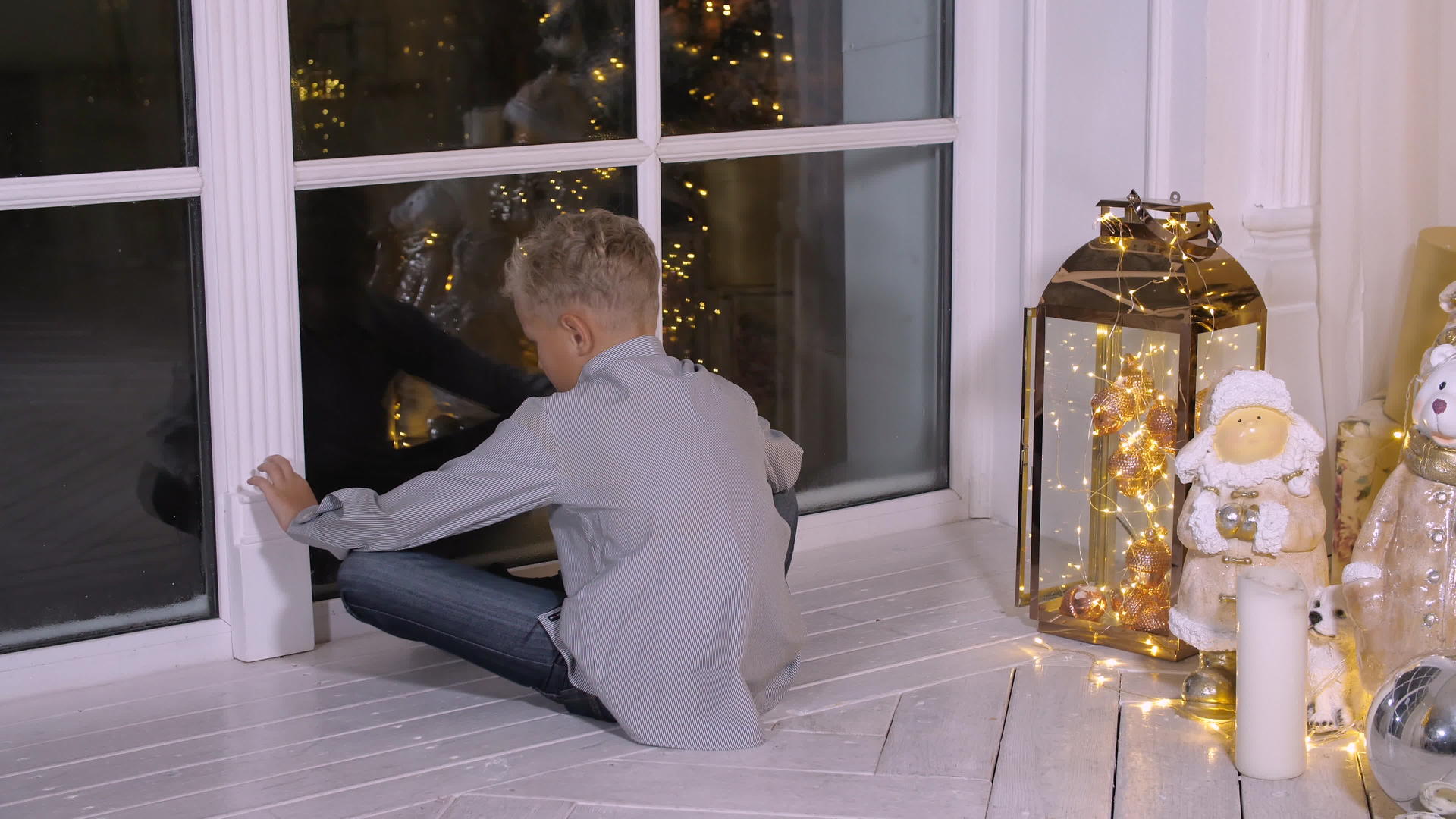 男孩坐在圣诞前夕的窗户旁边在客厅里等待圣克拉斯视频的预览图
