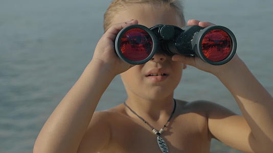 小男孩用望远镜看着海面上模糊的慢动作风景视频的预览图