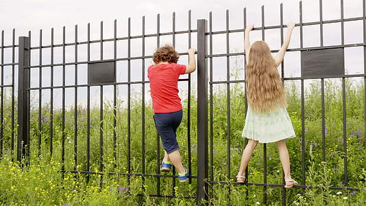 农村的男女孩子在暑假期间爬上铁栅栏在村里玩得很开心视频的预览图