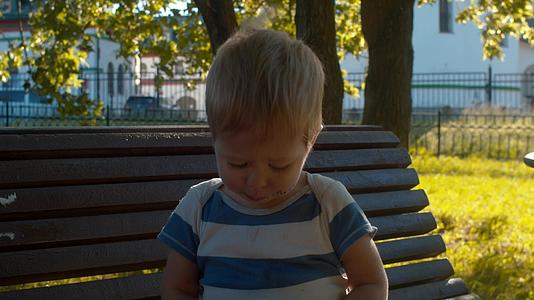 小男孩坐在长凳上吃馒头视频的预览图