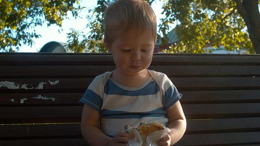 小男孩坐在长凳上吃馒头视频的预览图