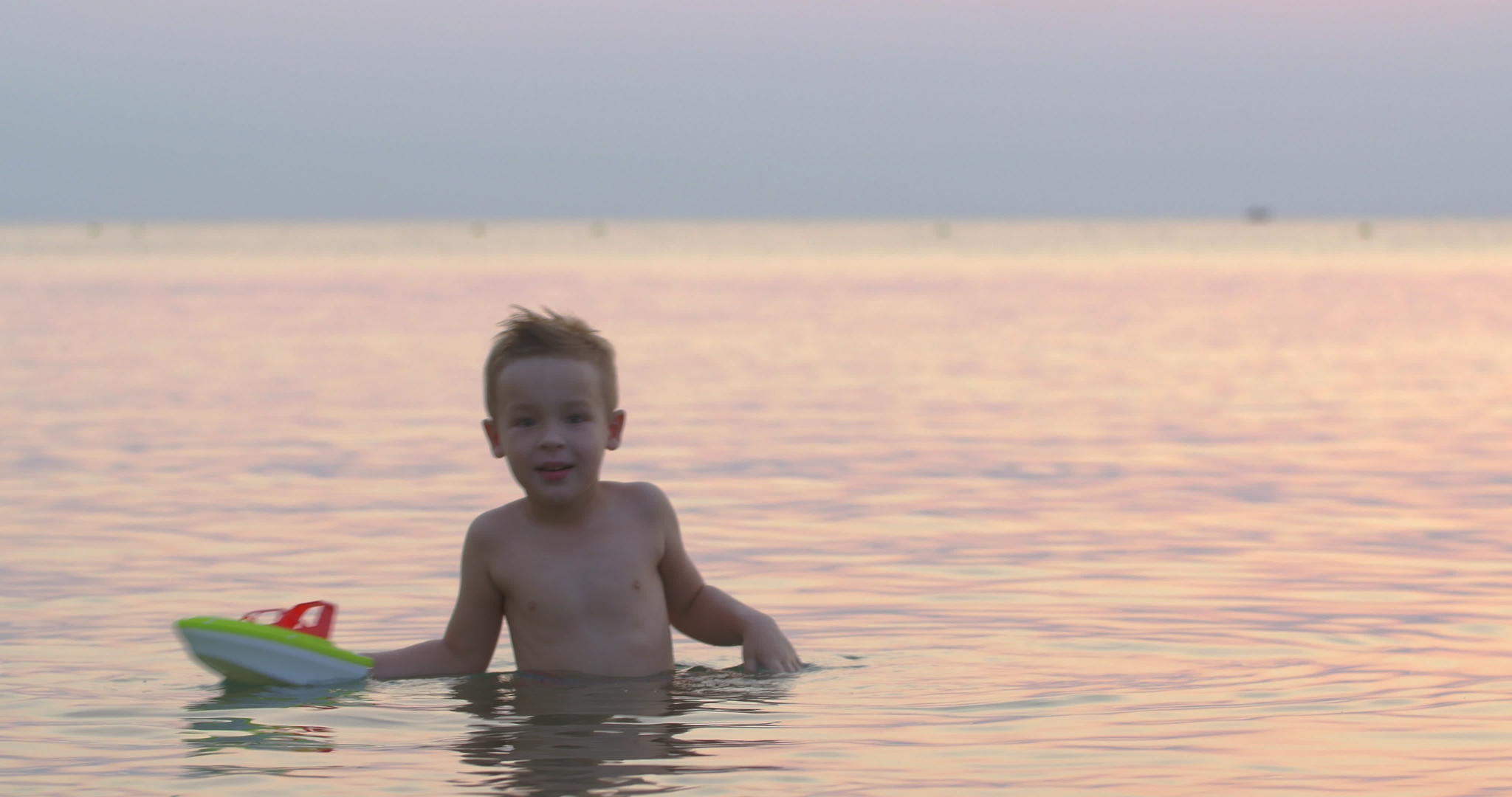 男孩在海上玩玩具船视频的预览图