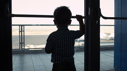 男孩看着机场窗外的小男孩视频的预览图