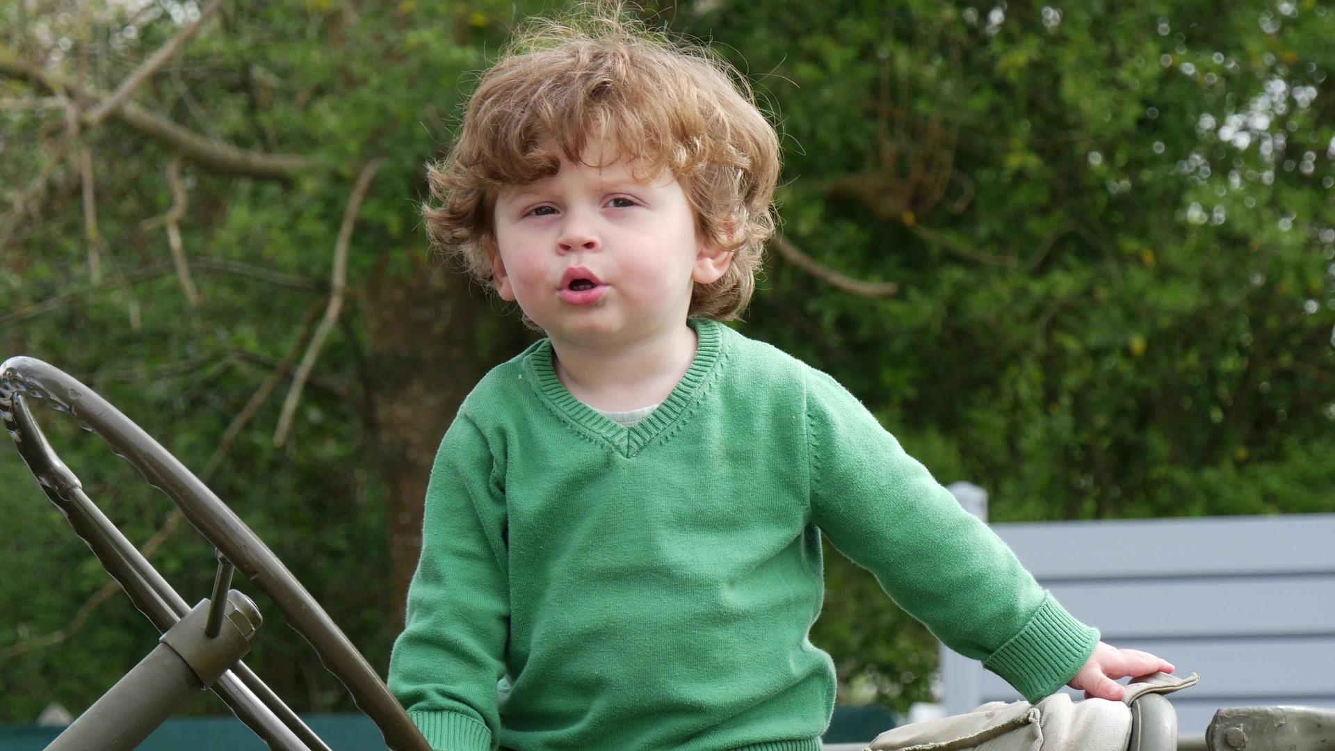 小男孩穿着绿色毛衣在户外玩耍视频的预览图