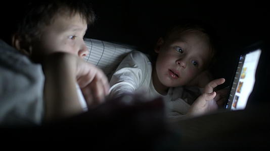 两个小男孩试图在晚上用平板电脑看电影视频的预览图