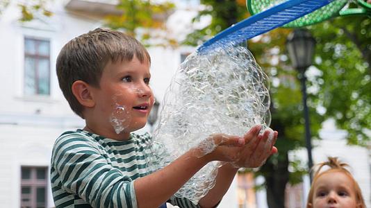 在肥皂泡秀中积极情绪化的男孩快乐微笑的孩子玩肥皂泡泡视频的预览图