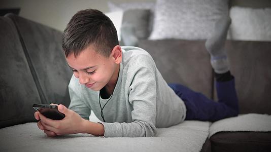男孩躺在沙发上玩电子游戏和微笑的沙发游戏视频的预览图